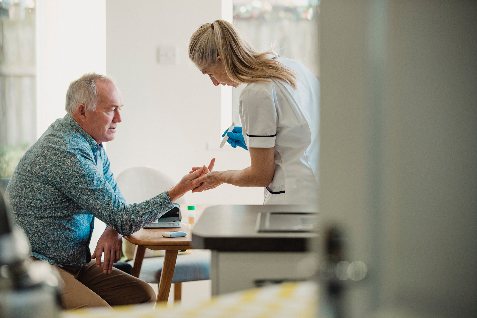 Nurse checking a patient's sugar levels at home. 