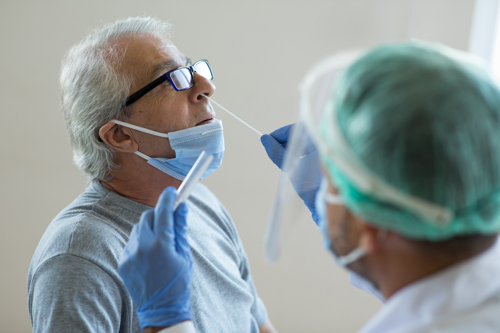 A man receiving a COVID-19 test by a healthcare professional. 