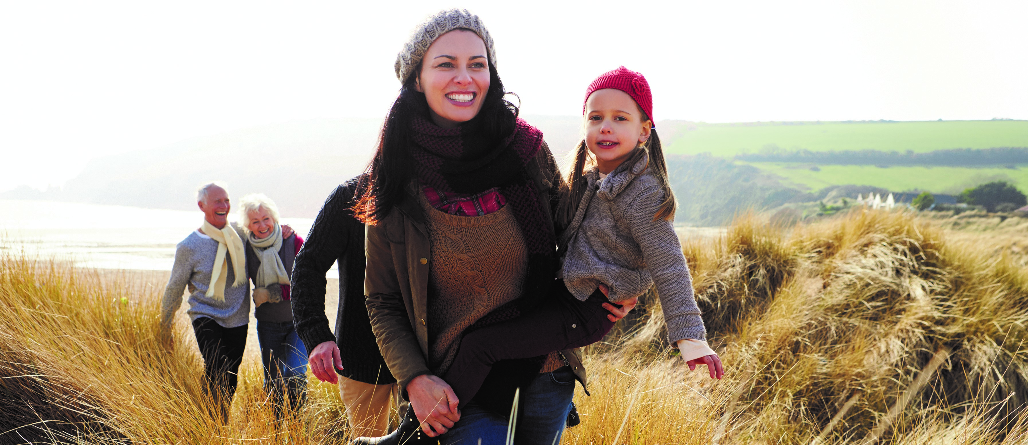 A family out of a walk in a field by the sea. 
