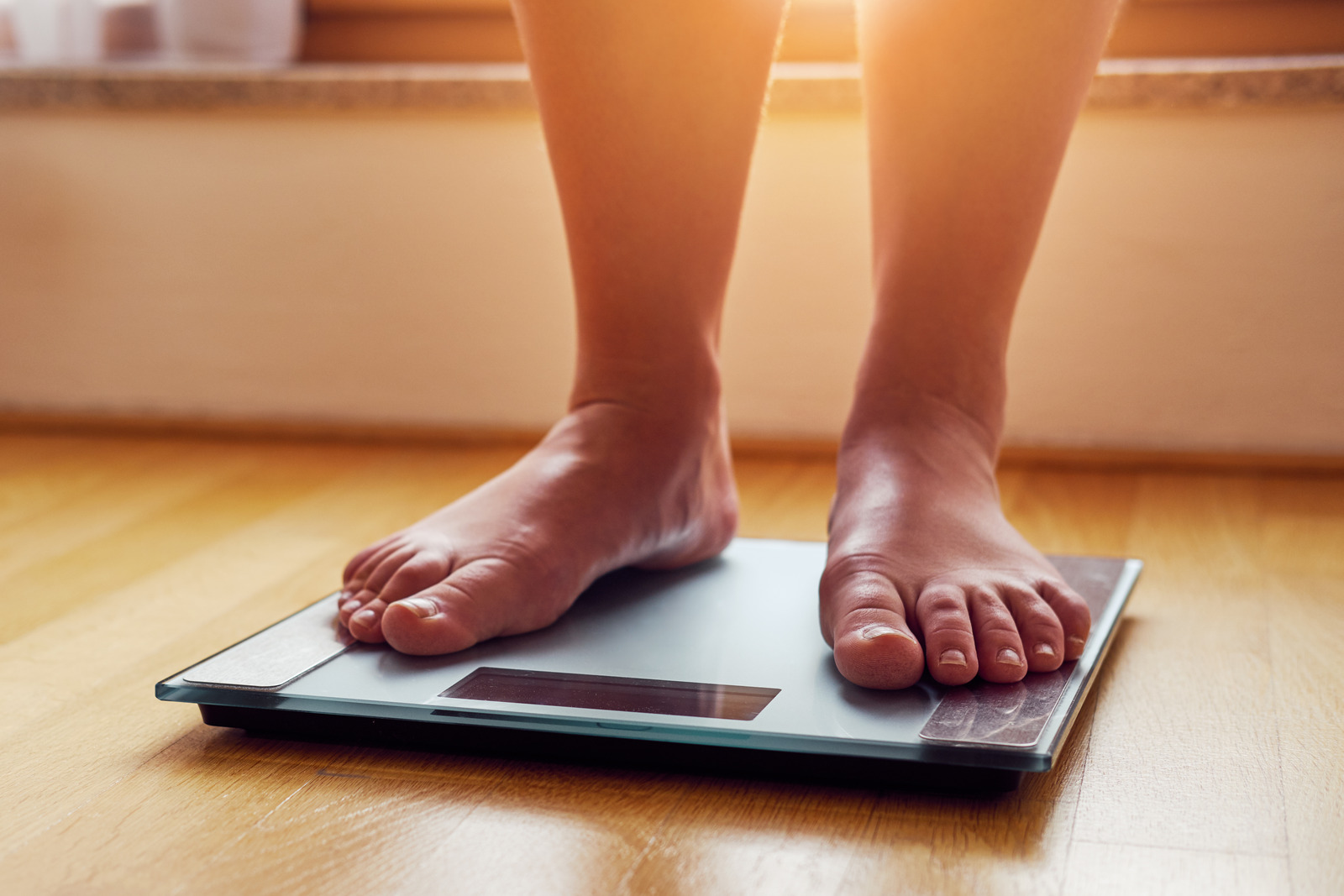 A person weighing themselves on scales. 
