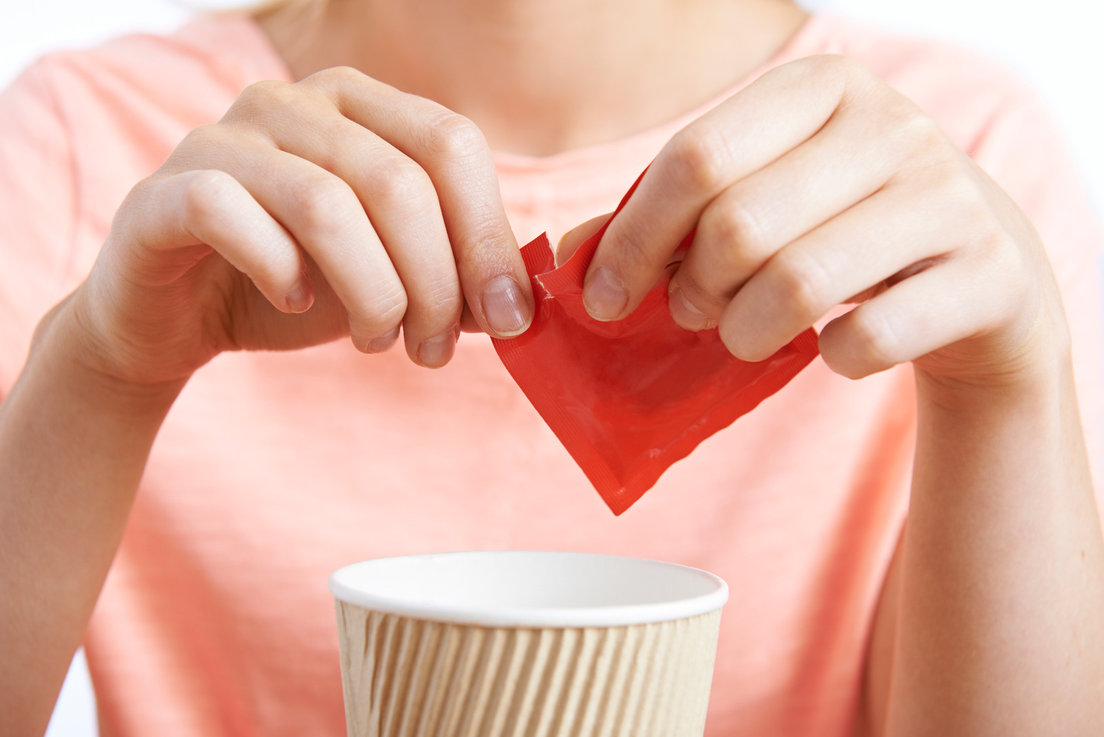 Woman Adding Artificial Sweetener To Drink